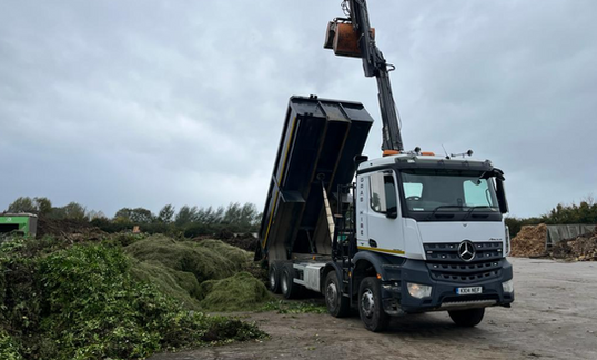 Truck unloading tree trimming debris.